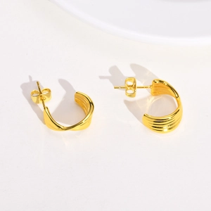 Detailed view of golden twisted hoop earrings with textured finish and butterfly backing