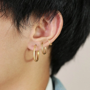 Détail de trois tailles différentes de créoles en or poli portées sur une oreille
