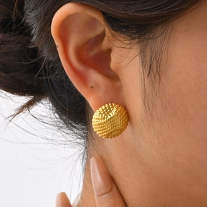 Close-up of golden stainless steel embossed round stud earrings with textured pattern