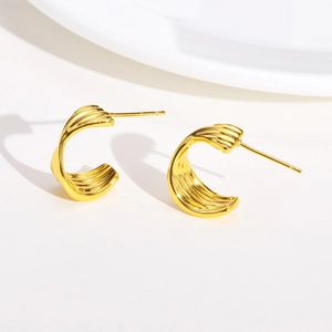 Close-up of gold-plated C-shaped earrings showing fine ripple texture and metallic luster