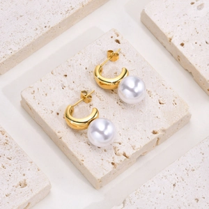 Détail macro des boucles d'oreilles en acier inoxydable doré en C avec perles blanches
