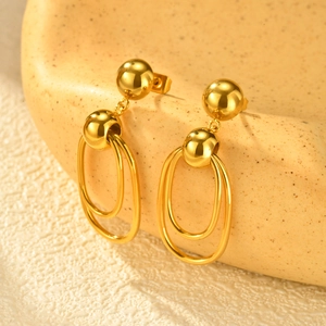 Polished gold stainless steel oval drop earrings displayed on a ceramic tray