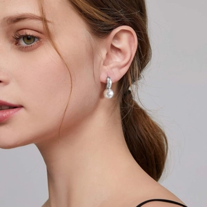 Gros plan sur une boucle d'oreille élégante en acier inoxydable et perle sur un mannequin