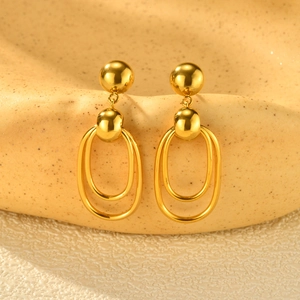 Macro detail of gold double oval hoop earrings with polished spheres and mirror finish
