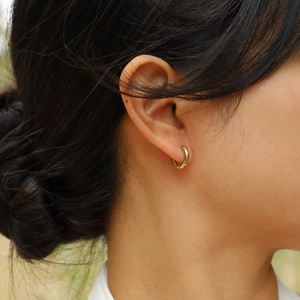 Créoles minimalistes en acier titane doré sur modèle féminin avec finition polie