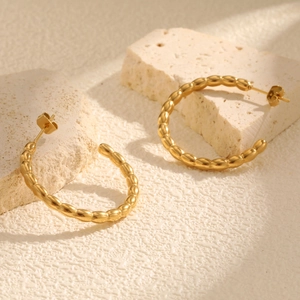 Golden stainless steel C-shaped hoop earrings with textured beads on stone blocks