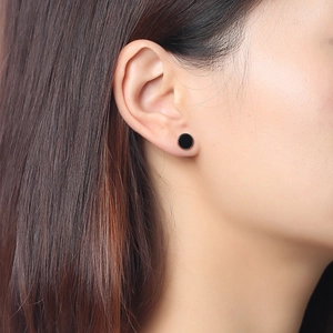 Gros plan d'un bouton d'oreille rond noir minimaliste avec bordure argentée sur un modèle