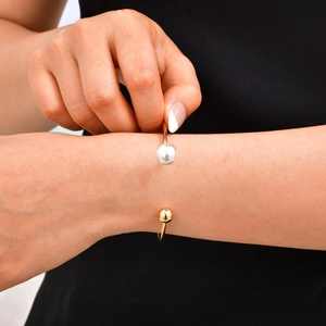Détail d'un bracelet jonc doré minimaliste avec perle et sphère sur un mannequin
