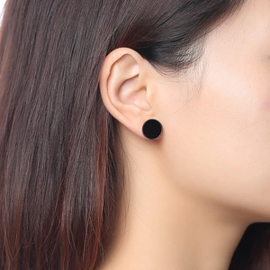 Gros plan d'une boucle d'oreille en acrylique noir minimaliste en or rose portée