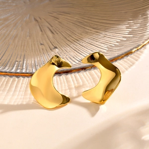 Nahaufnahme goldener unregelmäßiger geometrischer Ohrringe mit polierter Oberfläche