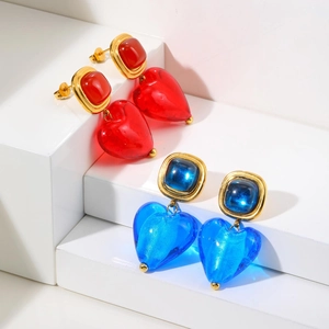 Gros plan de boucles d'oreilles cœur vintage en verre bleu et rouge sur socles dorés