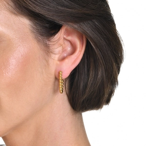 Close-up of a model wearing a gold beaded U-shaped huggie earring made of stainless steel