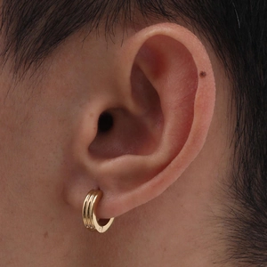 Close-up of triple-layered golden hoop earring worn on earlobe for unisex fashion