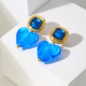 Détail de boucles d'oreilles cœur vintage avec résine bleu roi et finition dorée