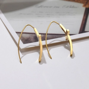 Détail de boucles d'oreilles dorées minimalistes avec finition en acier inoxydable poli