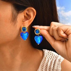 Détail de boucles d'oreilles cœur vintage avec résine bleue et base dorée