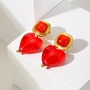 Détail de boucles d'oreilles cœur vintage dorées avec pendentifs en résine rouge