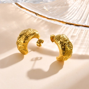 Macro shot of 18K gold plated C-shaped earrings with intricate textured engravings