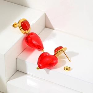 Gros plan de boucles d'oreilles cœur vintage dorées avec pendentif en verre rouge