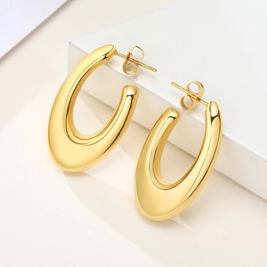 Polished gold hollow U-shaped geometric earrings on a minimalist white stone pedestal