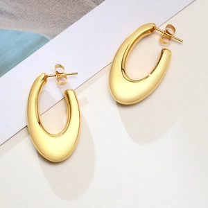 Close-up of polished golden U-shaped hollow earrings with reflective metallic finish