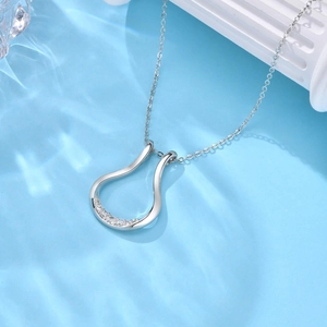 Dettaglio della collana in argento a forma di U con zirconi su sfondo con riflessi d'acqua