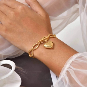 Détail d'un bracelet doré avec pendentif cœur et fermoir à bascule sur un poignet