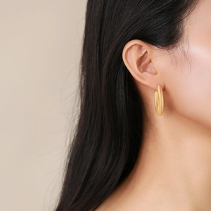 Minimalist golden stainless steel oval hoop earrings worn by a model for a modern look