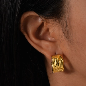 Modern 18K gold stainless steel C-shape earrings with irregular hammered texture on model