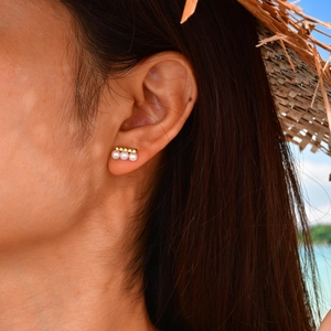 Close-up of elegant French style gold stud earrings with three pearls on female model