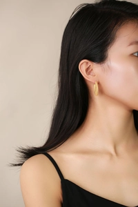 Close-up of elegant golden double spiral geometric earrings on model with soft lighting