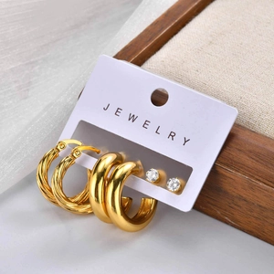 Detailed set of three golden twisted hoops, wide gold rings and clear zircon stud earrings