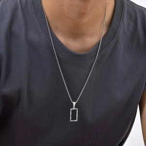 Close-up of men's square black pendant necklace on model with engraved metal details