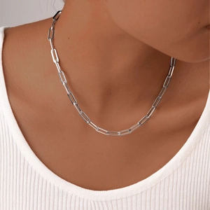Close-up of a minimalist silver paperclip chain necklace worn on a model neckline