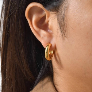 Close-up of model wearing 18K gold-plated thick hoop earrings with polished metal finish