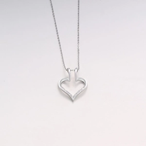 Dettaglio di una collana con ciondolo a cuore argento e zirconi su sfondo bianco puro
