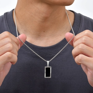 Close-up of men's geometric black acrylic square pendant with silver textured metal frame