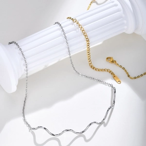 Detail shot of wavy gold and silver necklaces on white columns with 18K hallmarks