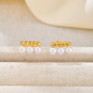 Detail of French style gold bar earrings with diamond-cut texture and white pearls