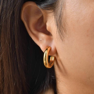 Polished chunky gold C-shaped hoop earrings on model showing high-shine metal texture