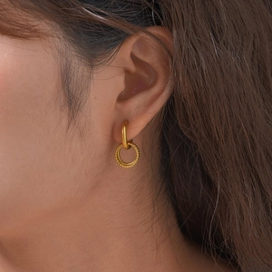 Detailed close-up of a gold stainless steel earring with beaded texture on a model