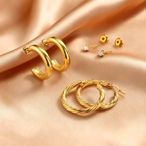 Detailed set of three gold earrings featuring smooth C-shape, twisted hoop, and zircon studs