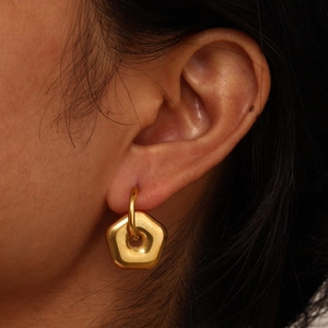 Close-up of geometric gold-plated pentagon hoop earrings on model with polished metal finish