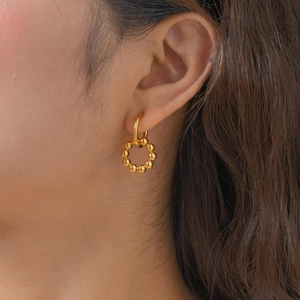 Detailed view of a woman wearing gold-toned multi-bead hoop earrings for a stylish look