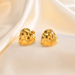 Détails de boucles d'oreilles cœur dorées avec texture tressée sur tissu en soie