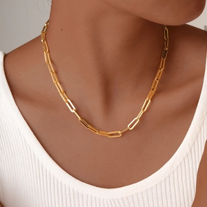 Close-up of golden stainless steel rectangular link chain necklace on model collarbone
