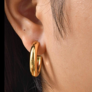 Close-up of chunky gold hoop earring worn by a model showcasing polished metallic shine