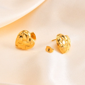 Gros plan sur des boucles d'oreilles cœur dorées avec texture tissée sur satin