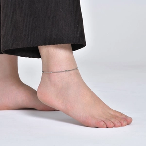 Close-up of minimalist silver snake chain anklet with small round beads on woman's ankle