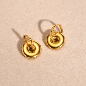 Macro view of gold stainless steel chunky hoop earrings with donut-shaped charms